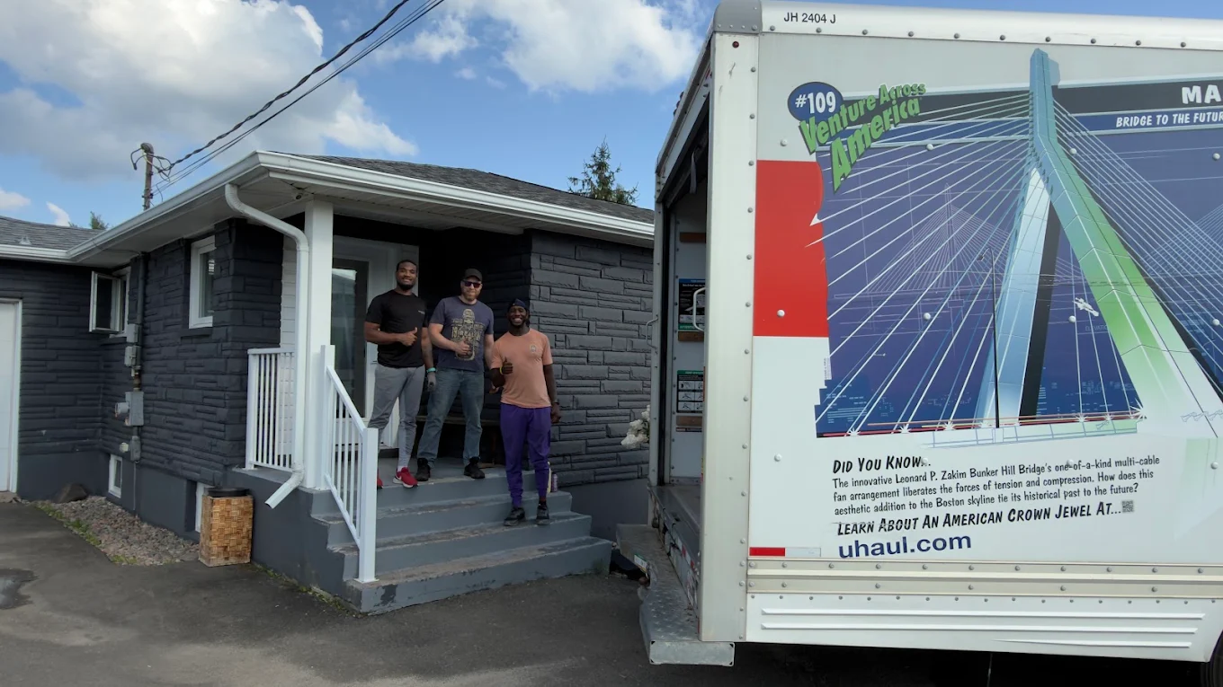 Three movers giving a thumbs up on a front porch beside their moving truck